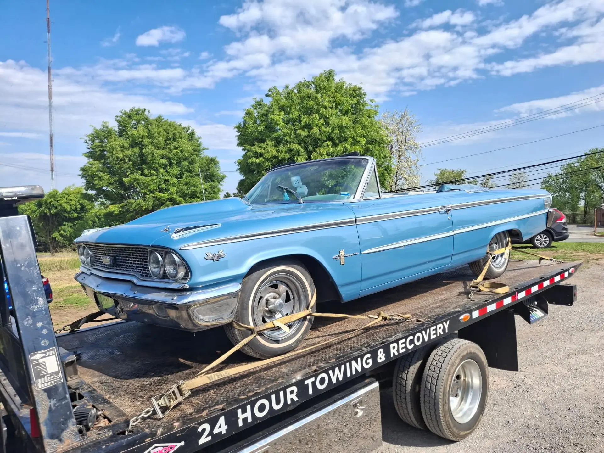 Blue classic convertible secured with wheel straps on a CARSTAR flatbed tow truck